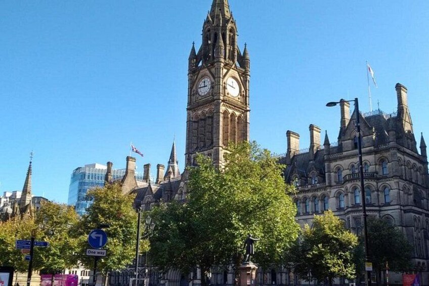 A historic building with a clock tower, surrounded by trees and modern buildings. 3