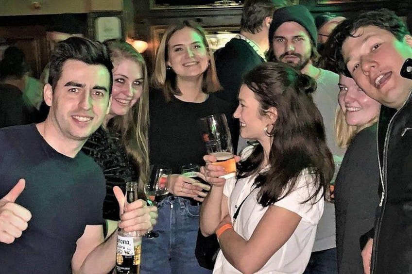 Een groep mensen bij een bijeenkomst, die drankjes vasthouden en met elkaar praten. 4