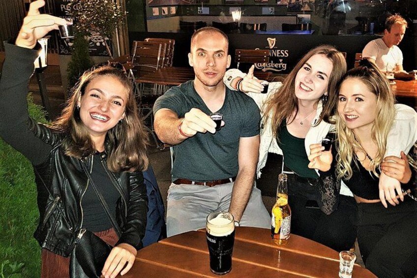 Een groep mensen zit aan een tafel in een restaurant, met een bierkruik en een glas bier op tafel. 5