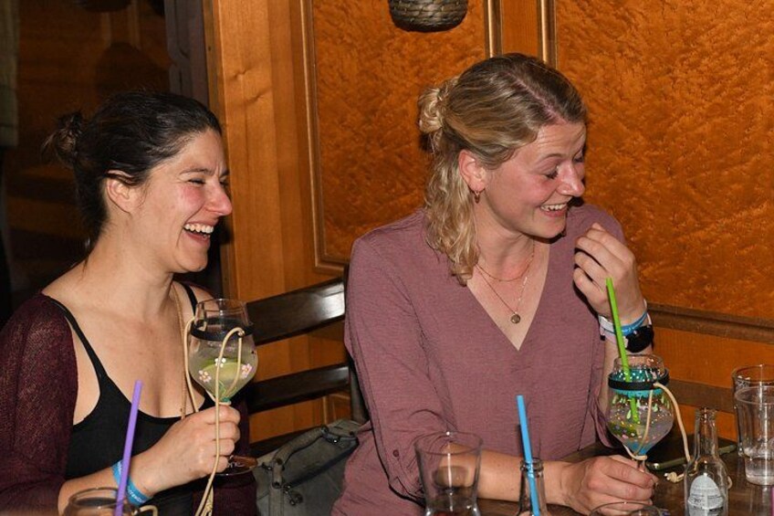 Deux personnes sont assises à une table, devant des boissons et un verre décoratif. 2