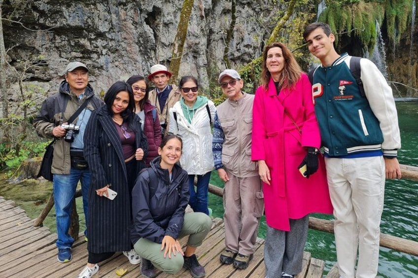 A group of people on a wooden dock near a rocky cliff and water. 4