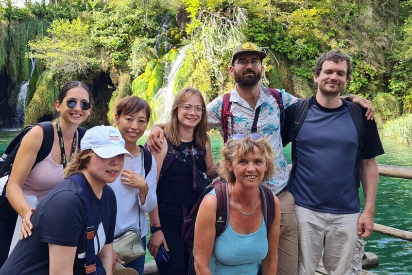 A group of people on a boat in a natural setting with greenery and a waterfall in the background. 2