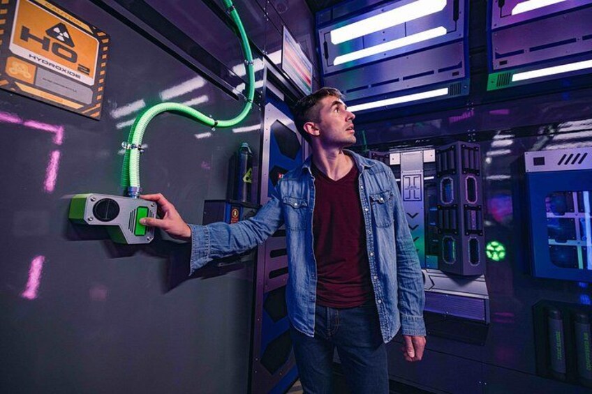 A person in a denim jacket interacting with a green and gray device on a wall with a sign reading 'HO2 HYDROGEN'. 2