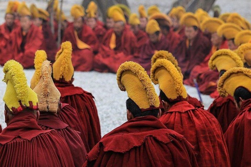 A group of people in red robes with yellow headgear, seated in a row. 4