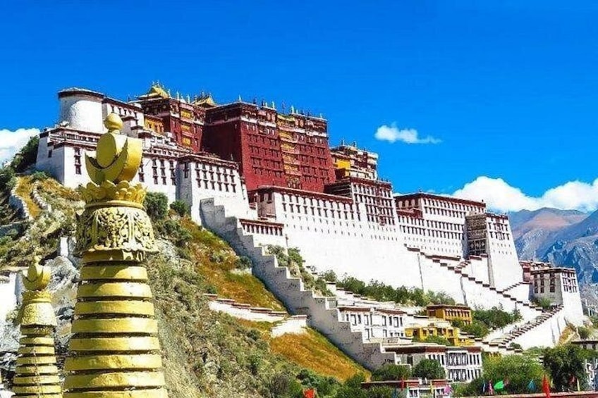A large, multi-tiered fortress-like structure with a red and white color scheme, surrounded by a mountainous landscape. 2