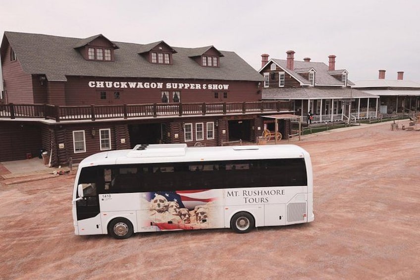 A white bus parked in front of the Chuckwagon Supper Show building. 3