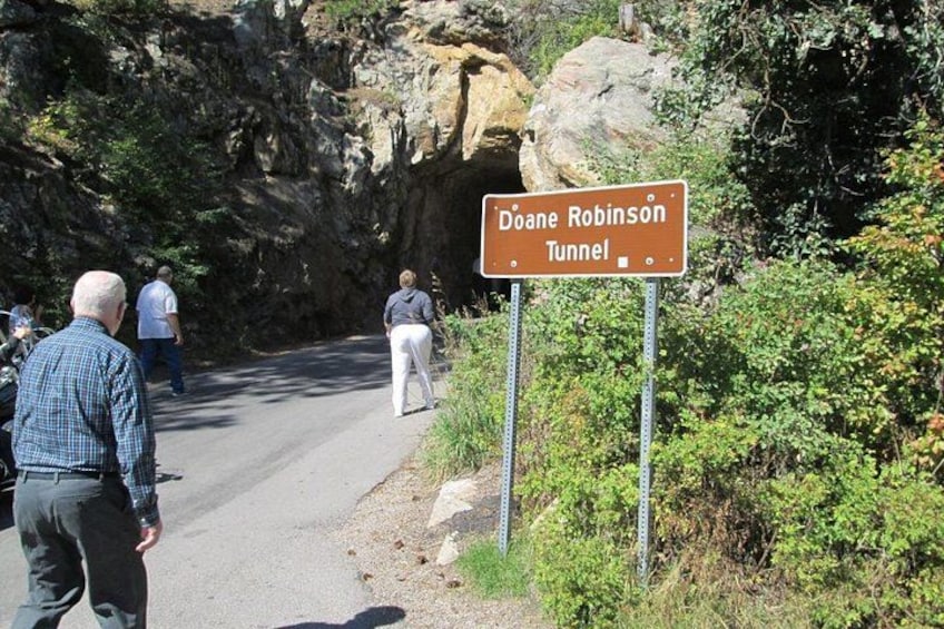 A road leading to Doane Robinson Tunnel with people walking and a rocky cliffside. 2