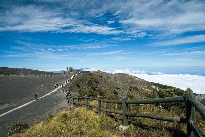A road with a wooden fence, a clear sky, and distant hills. 5