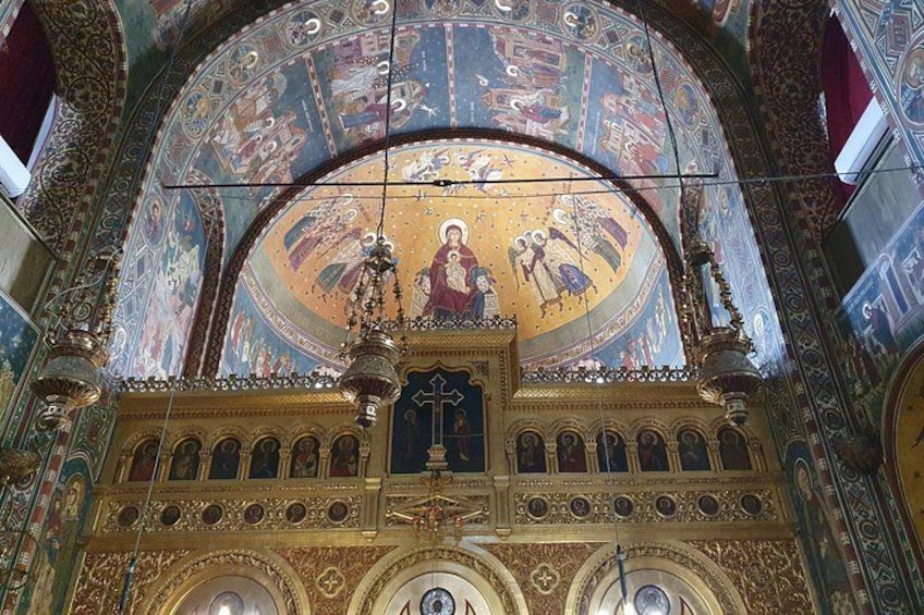 Een versierd kerkinterieur met een grote koepel, gedetailleerde mozaïeken en religieuze iconografie. 3