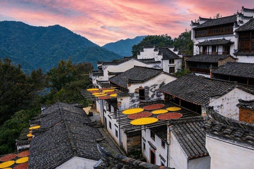 Traditional architecture with tiled roofs, a mountainous backdrop, and a sunset sky. 4