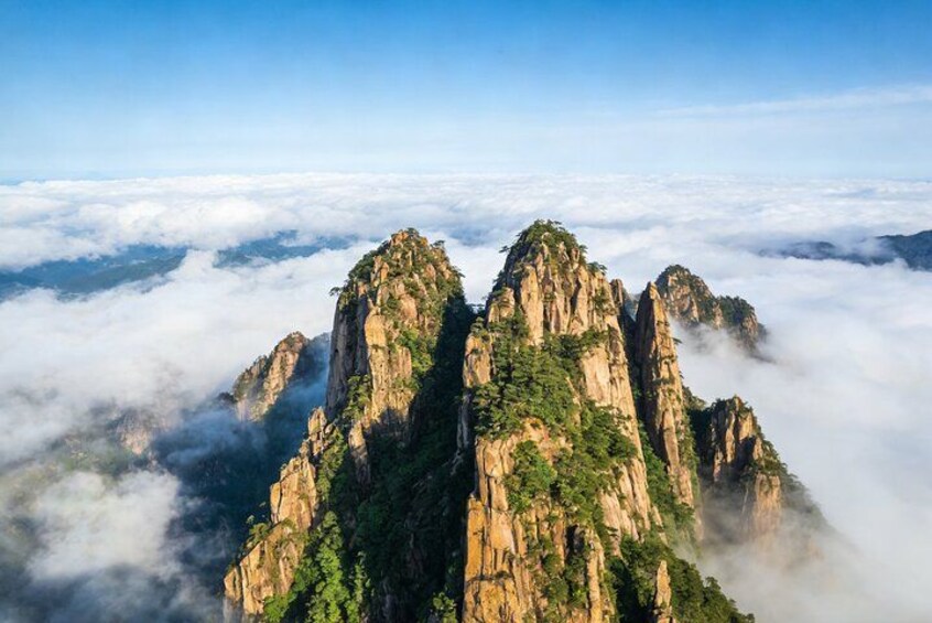 A mountain range with peaks covered in greenery, surrounded by clouds. 3