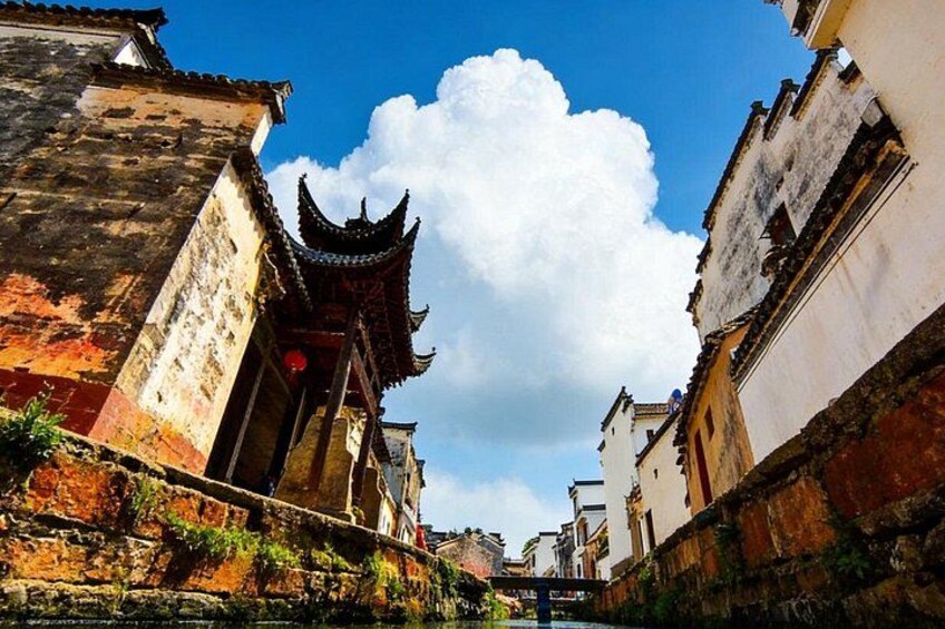 A narrow alleyway with traditional buildings, a prominent pagoda, and a clear blue sky. 5