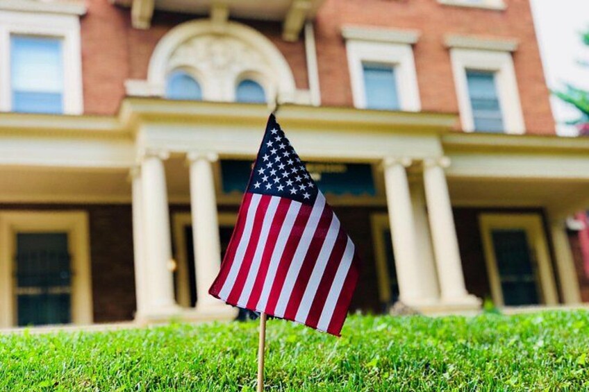 Una bandiera americana su un prato erboso di fronte a un edificio con colonne e un frontone. 2
