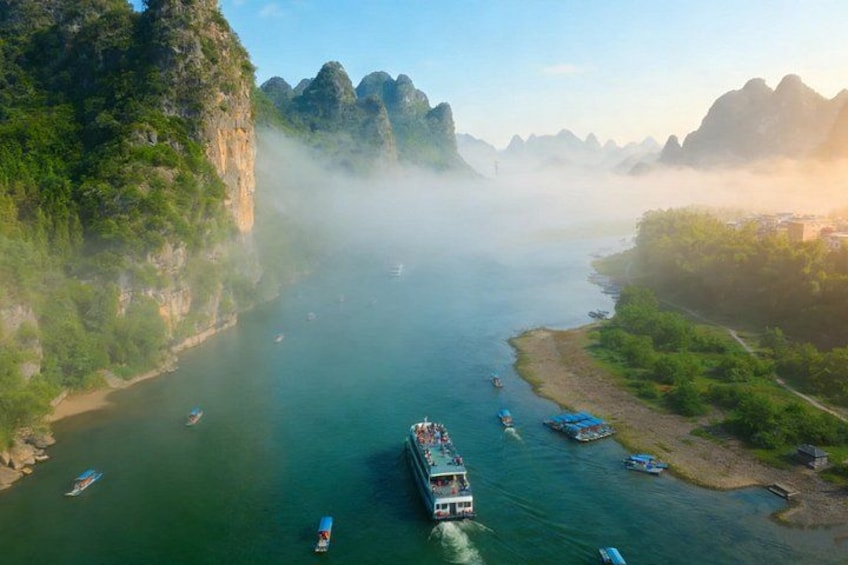 A river with boats, surrounded by cliffs and greenery. 1