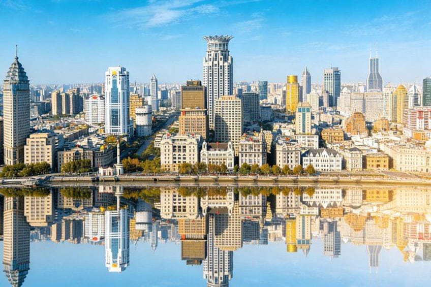 A city skyline with a river reflecting buildings, including a prominent tower and several modern skyscrapers. 2
