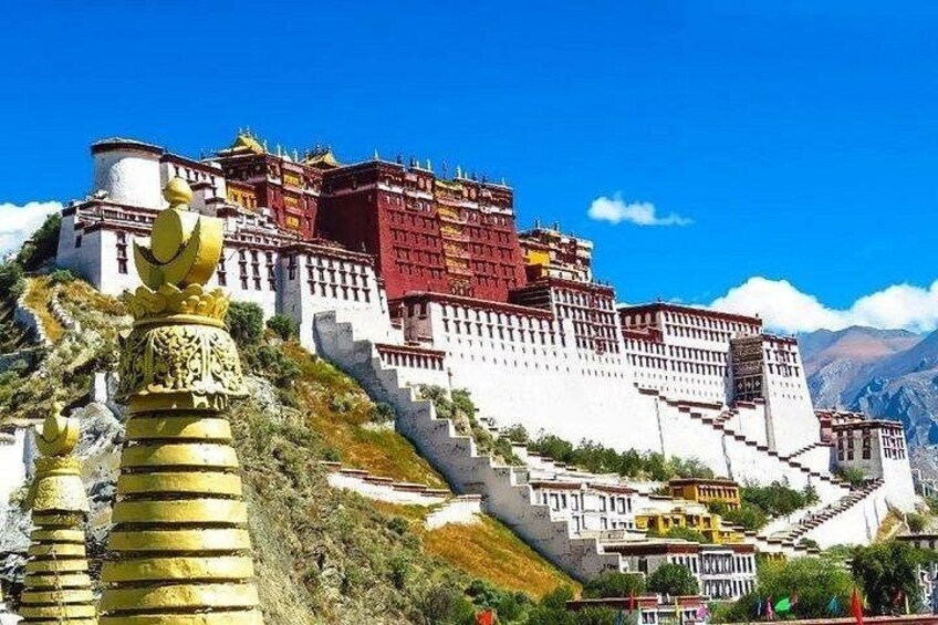 A large, multi-tiered fortress-like structure with a red and white color scheme, surrounded by a mountainous landscape. 2