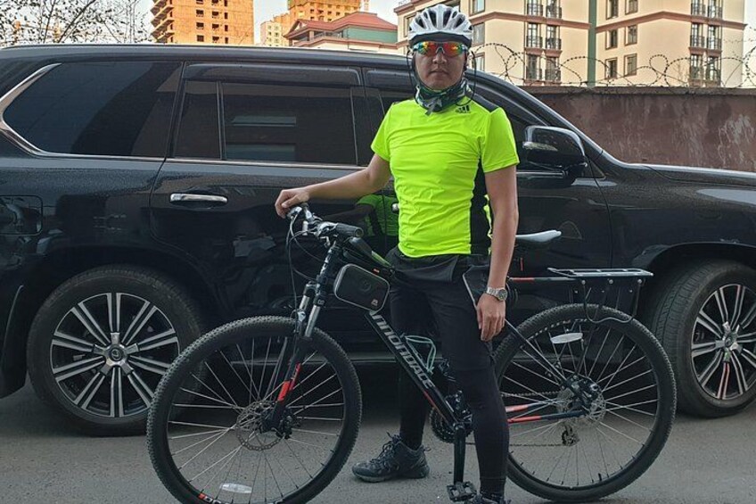 Una persona de pie junto a una bicicleta, con un SUV negro al fondo. 5