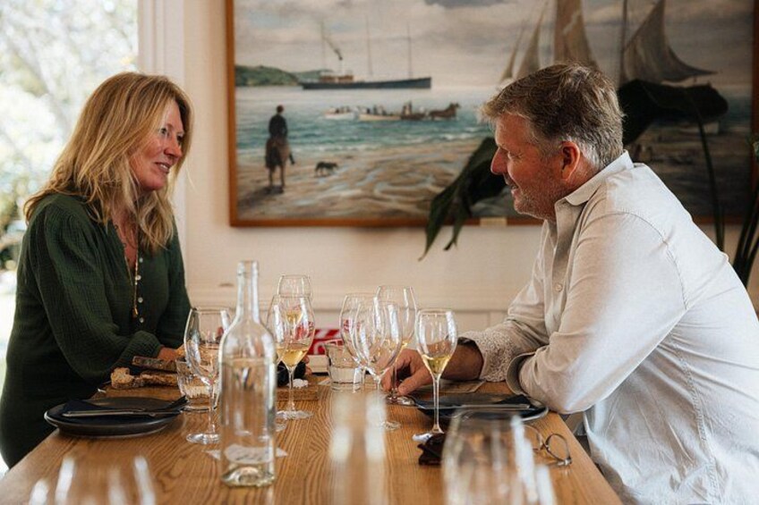 A dining table with wine glasses and bottles, a painting of a seascape, and a wooden table. 3