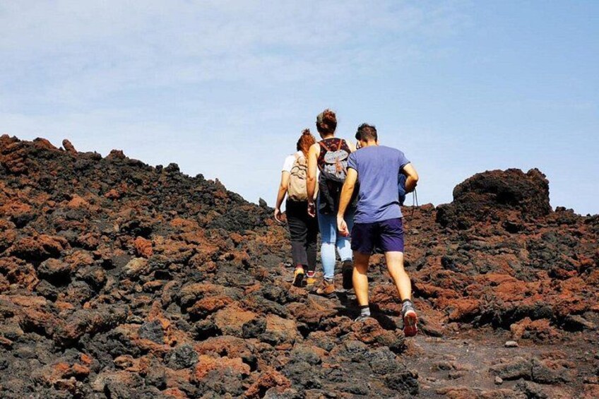 Un gruppo di persone fa trekking su un terreno roccioso, con cielo sereno. 2
