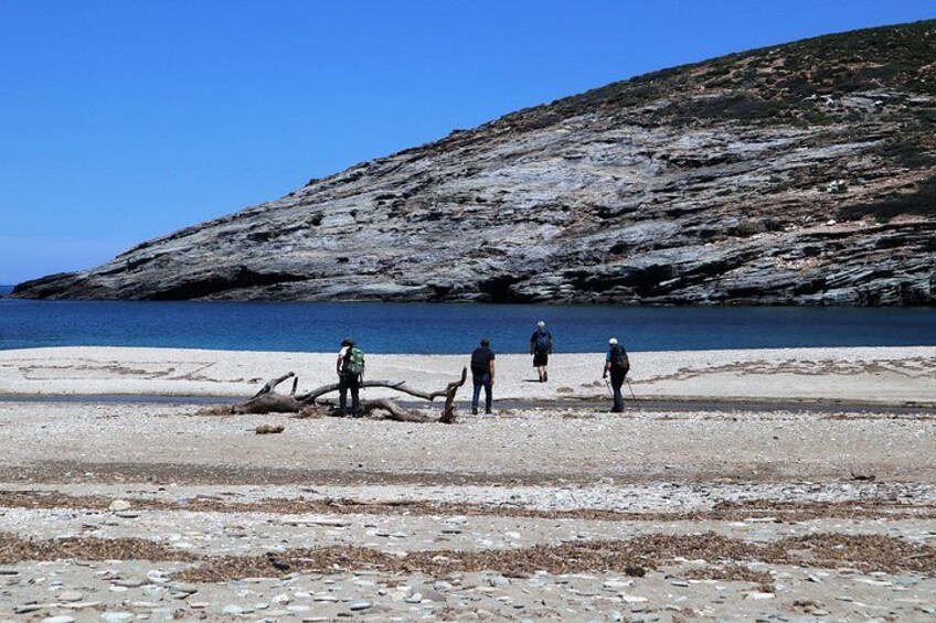 A rocky shoreline with people walking and standing. 2