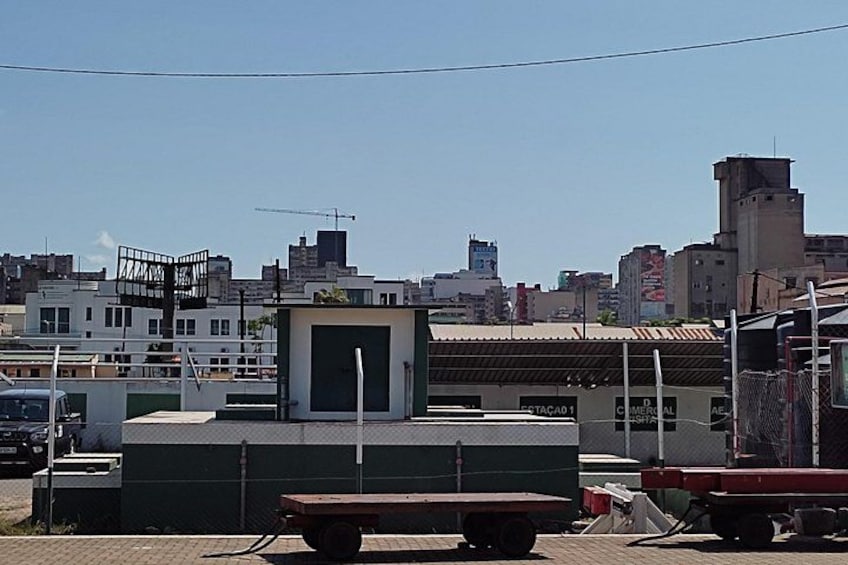 Un sitio de construcción con un edificio verde, una estructura blanca pequeña y un camión rojo. 1