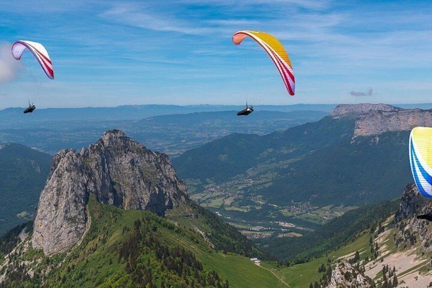 Des parapentes survolent un paysage montagneux, avec des pics rocheux et des vallées verdoyantes. 2
