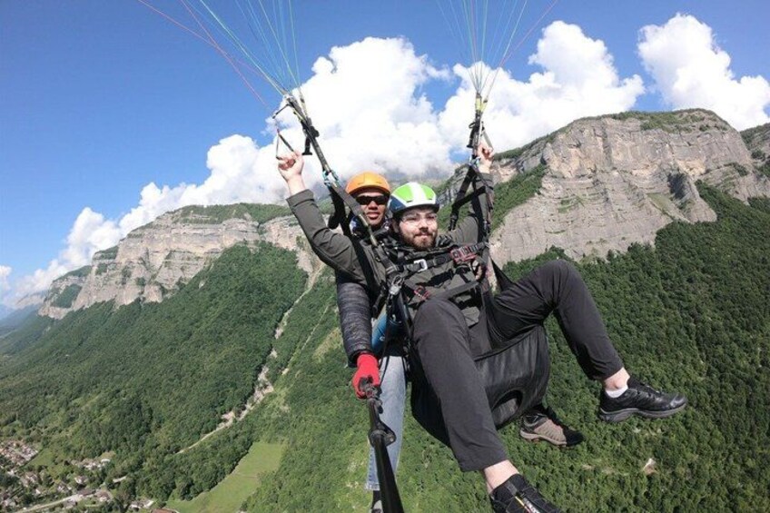 Dos personas haciendo parapente, con montañas y un cielo despejado al fondo. 3