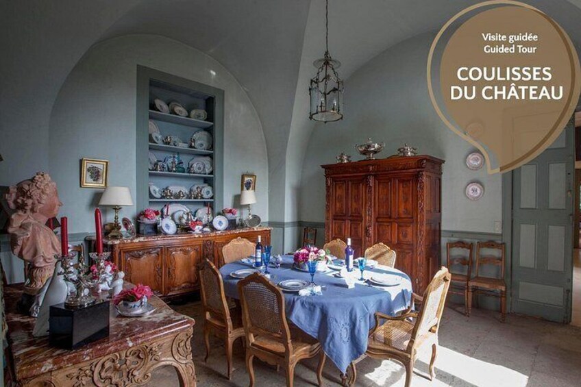 Een eetkamer met een gedekte tafel, omringd door stoelen en een houten kast. 2