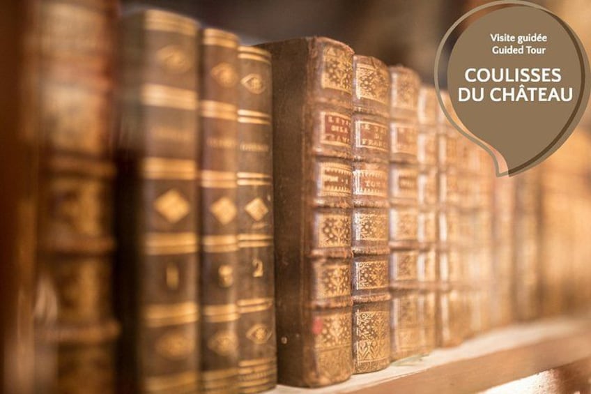 A row of old, ornate books with a label indicating a guided tour of the château. 3