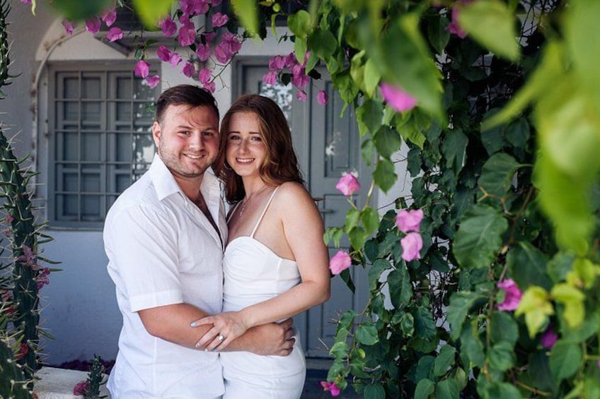 Een stel omhelst voor een huis met roze bloemen en groene begroeiing. 5