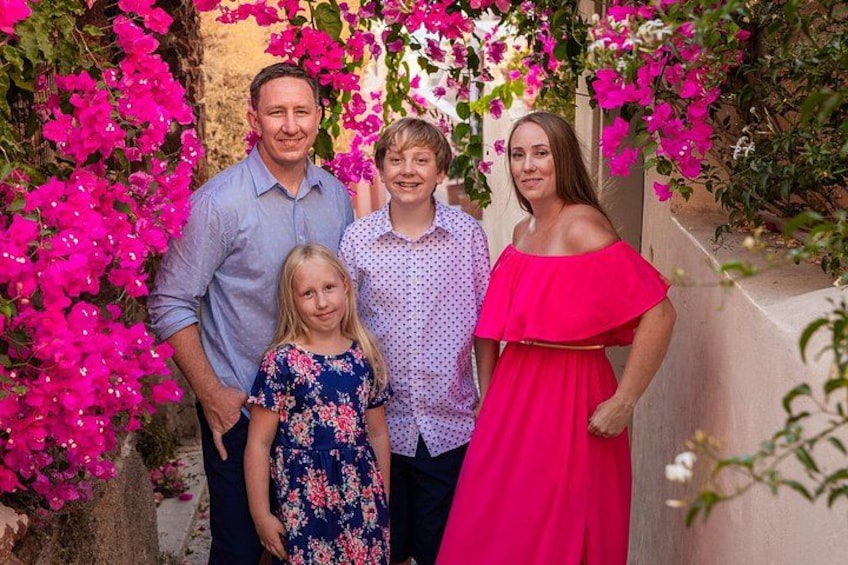 Een gezin van vier voor een muur vol roze bougainvillea's. 4