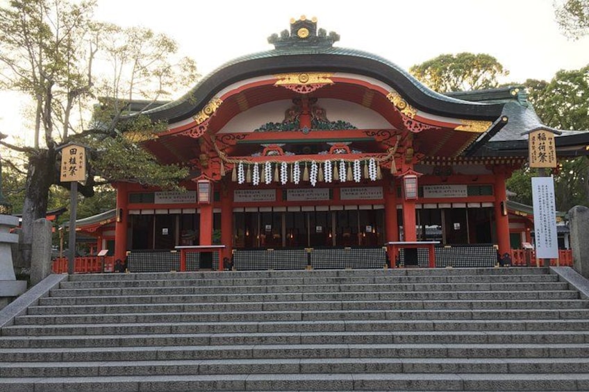 A traditional Japanese temple with a red and gold roof, steps leading up to it, and a signboard. 4
