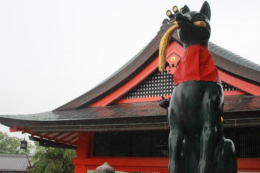 A traditional Japanese building with a red roof and a large black statue of a mythical creature. 5