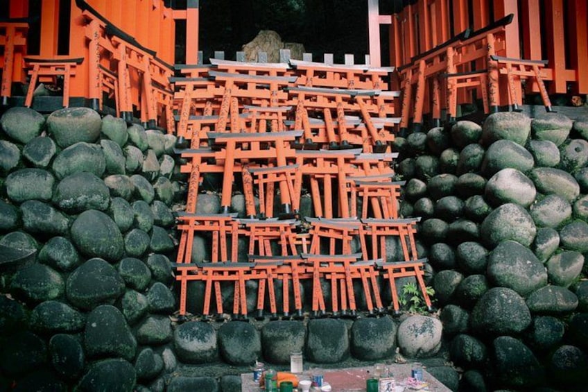 A traditional Japanese torii gate structure with a stone base, surrounded by a stone wall. 2