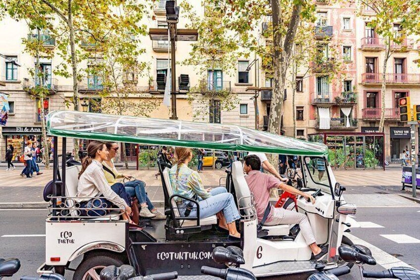A group of people on a golf cart in an urban setting with buildings and trees. 2