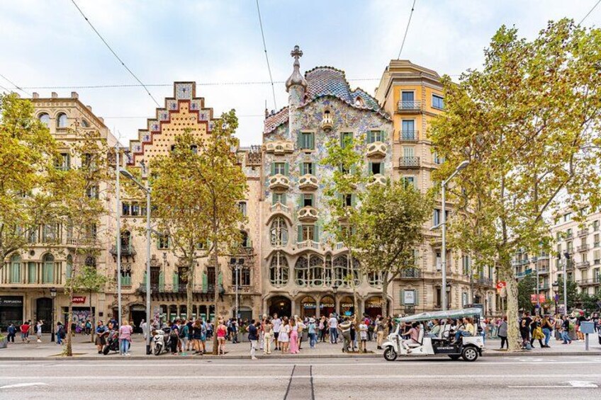 A historic building with ornate architecture, a tram, and a crowd of people. 3