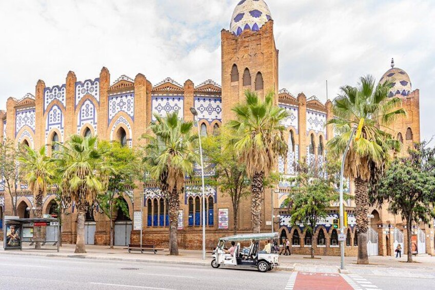 A historic building with intricate tile work, palm trees, and a street with a white car. 2