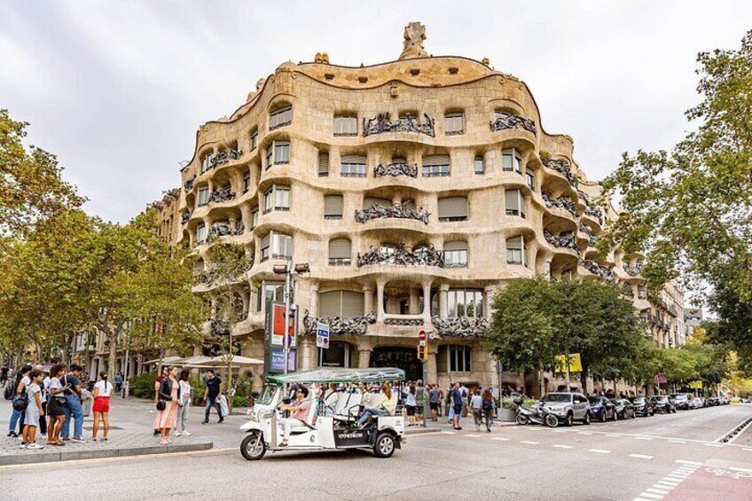 A building with balconies and a street with people and cars. 3