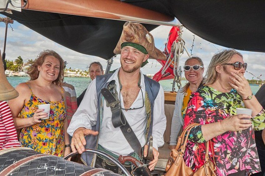 A group of people on a boat with a man wearing a pirate hat and a woman in a colorful dress. 3