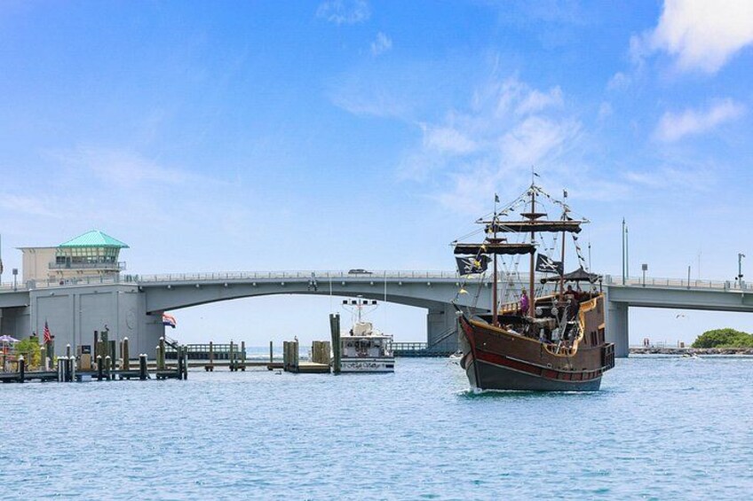 A historic ship on the water, a bridge, and a small building with a green roof. 2