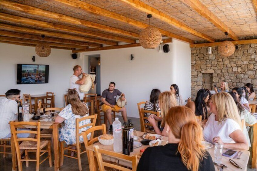 A rustic outdoor dining area with wooden tables and chairs, stone walls, and hanging light fixtures. 3