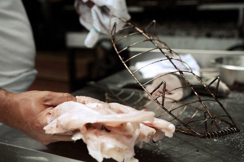 A person holding raw meat with a metal rack in a kitchen setting. 1