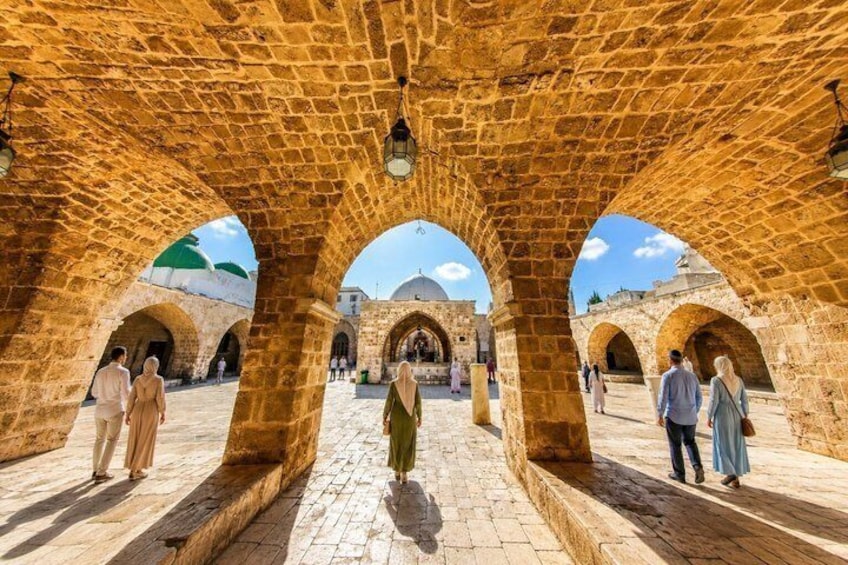 An ancient stone archway with people walking through. 3