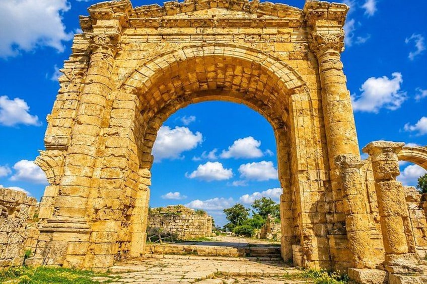 Un arc en pierre antique, soutenu par des colonnes, se détachant sur un ciel bleu clair. 2