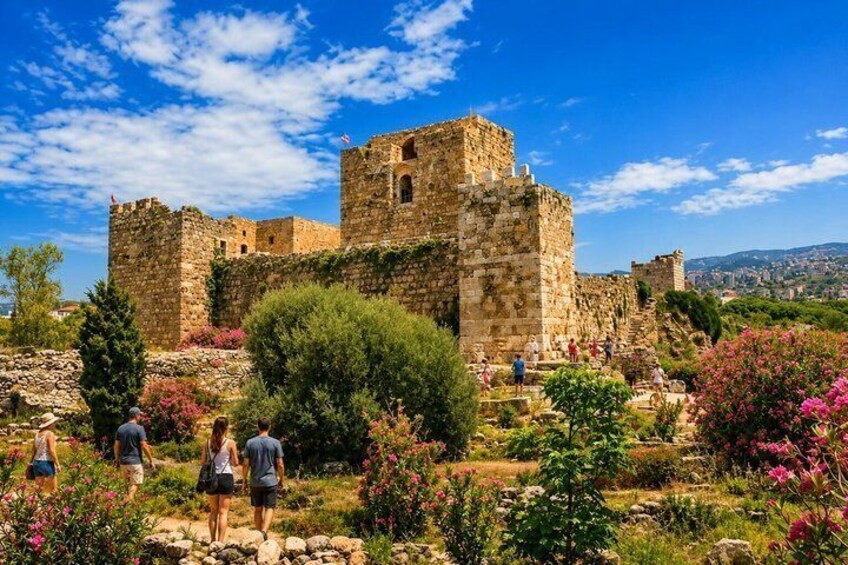 An ancient stone castle with tourists walking around. 3