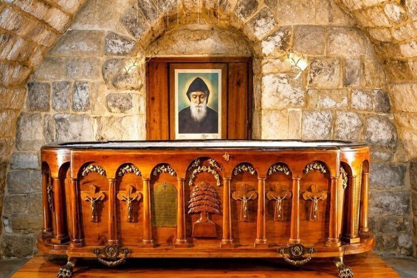 Un iconostasio de madera con iconos religiosos y un retrato enmarcado en la parte superior, sobre un muro de piedra. 4