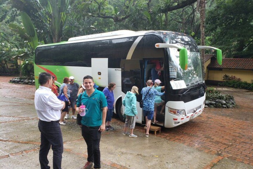 A group of people boarding a bus in a tropical setting with lush greenery. 4