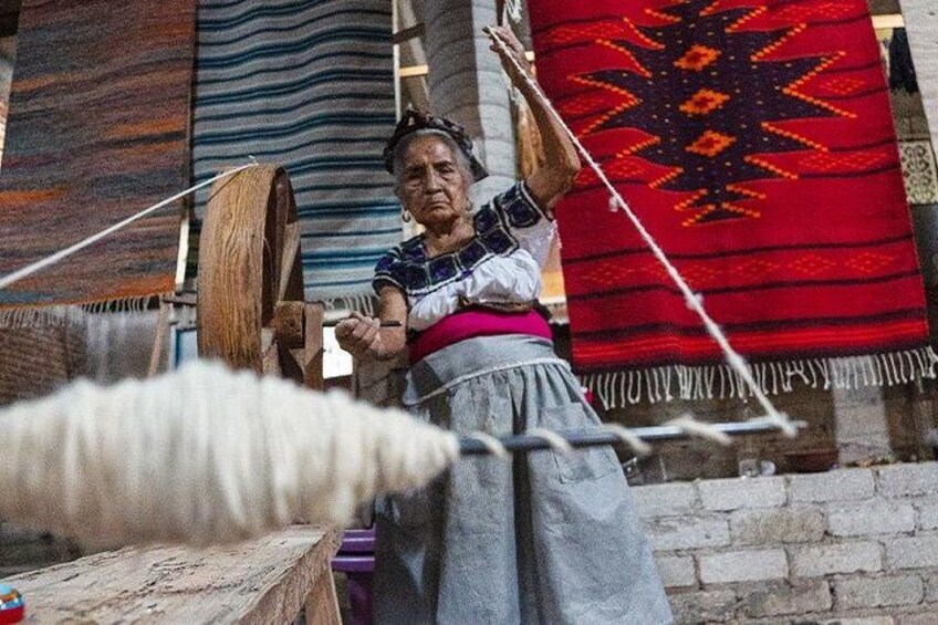 Une personne qui tisse sur un métier à tisser traditionnel, entourée de tissus aux couleurs vives. 2