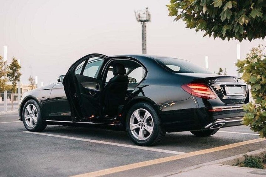 A black car parked on the side of a road with its door open. 1
