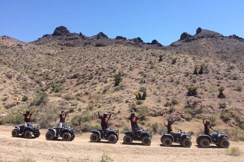 A group of people on ATVs in a desert landscape with rocky hills in the background. 2